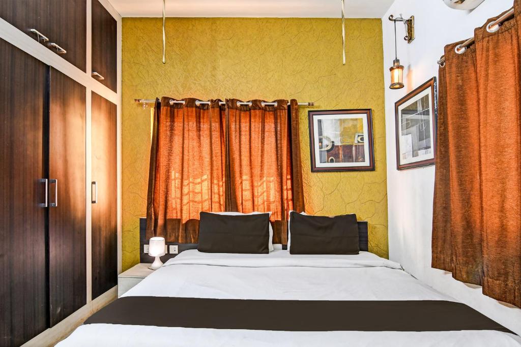 a bedroom with a large bed with an orange curtain at Hotel O Home Bm-x in Khandagiri