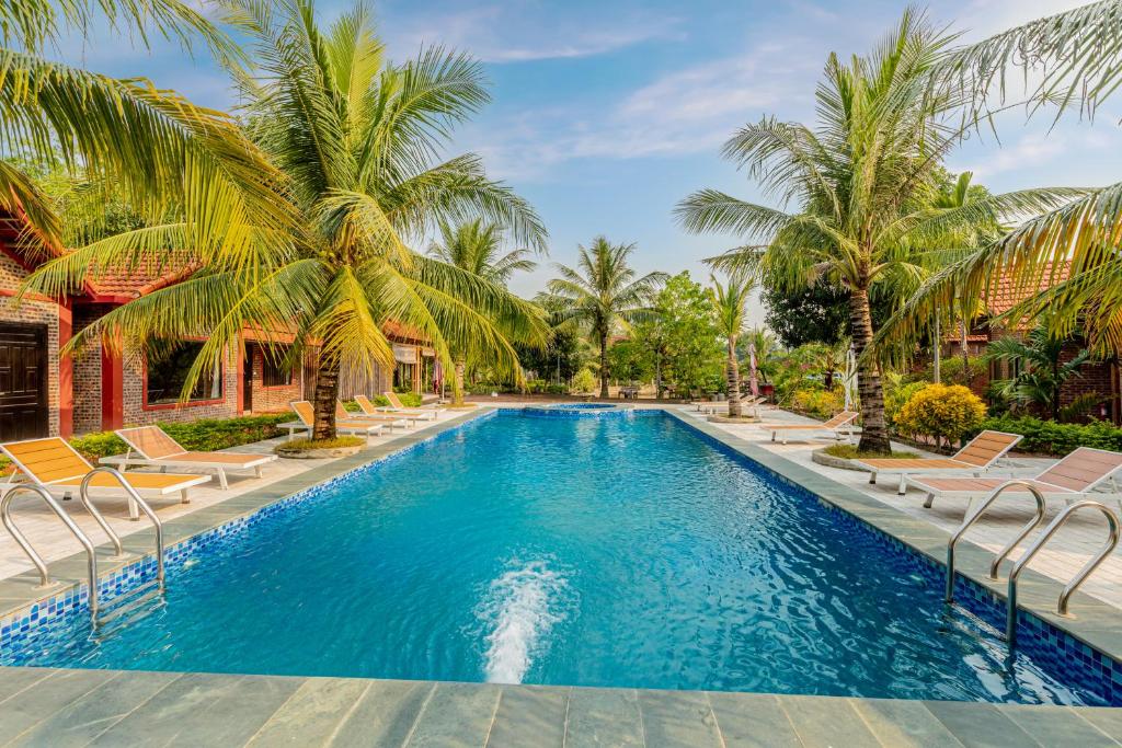 a swimming pool with chairs and palm trees at Tam Coc Green Garden Bungalow in Ninh Binh