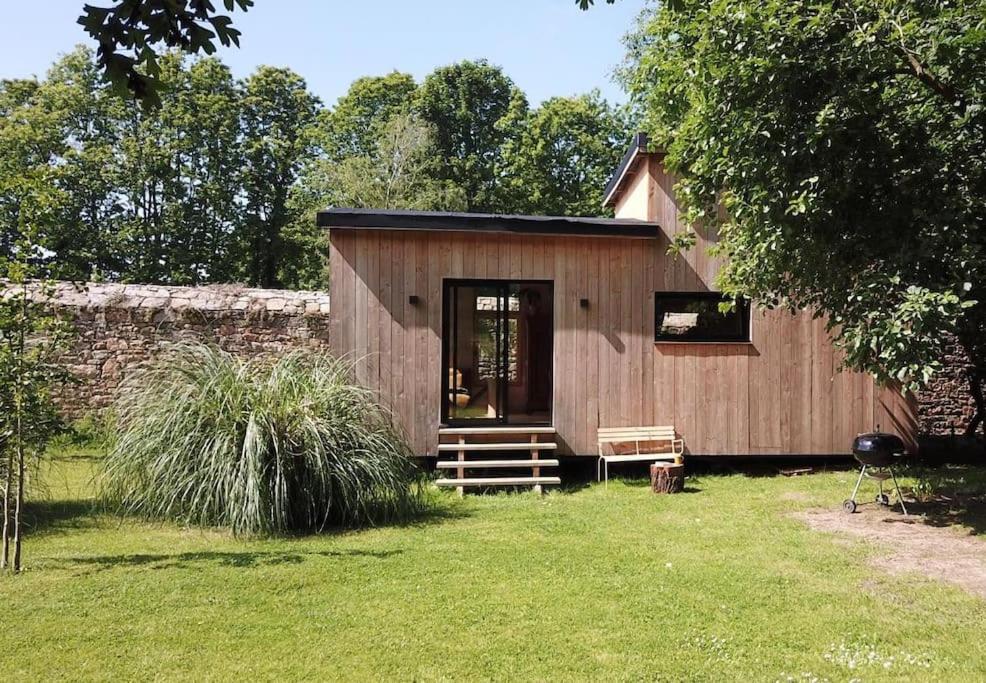une petite cabane en bois avec un banc dans une cour dans l'établissement Tiny à l'orée des bois, à Locquénolé