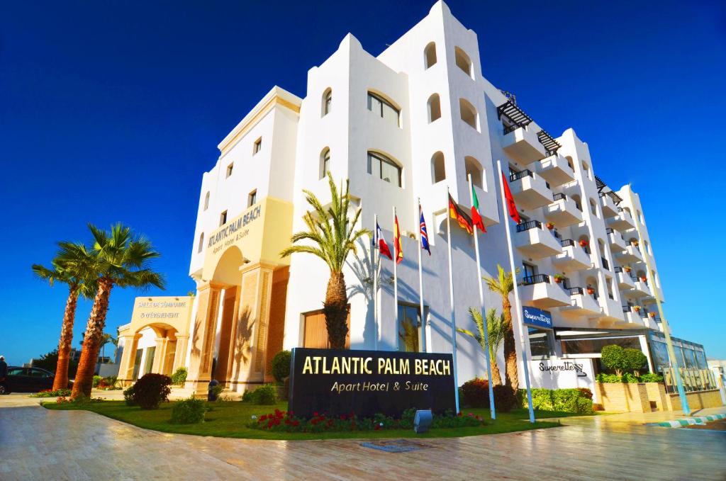 a large white building with palm trees in front of it at Atlantic Palm Beach in Agadir