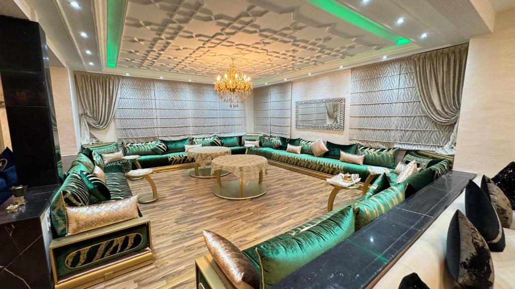 a lobby with green leather couches and a chandelier at magnifique appartement de 250m2 dans villa avec piscine in Fès