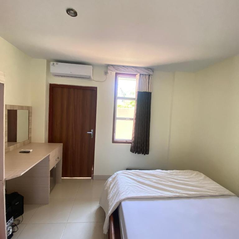 a bedroom with a bed and a desk and a window at Labuan Bajo room in Labuan Bajo