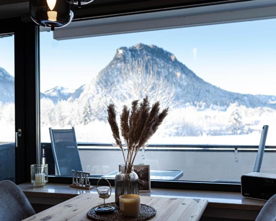 a table with a view of a mountain through a window at Jopachalets Pfronten in Pfronten
