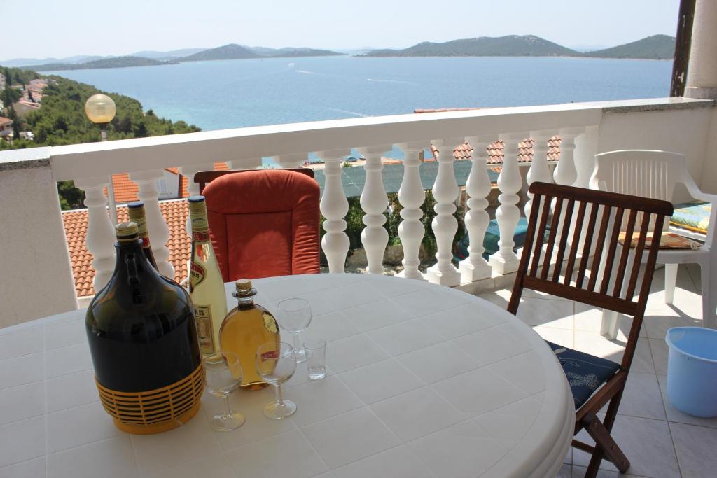 einen Tisch mit 2 Flaschen und Weingläsern auf dem Balkon in der Unterkunft Apartments Toni Na Moru in Drage