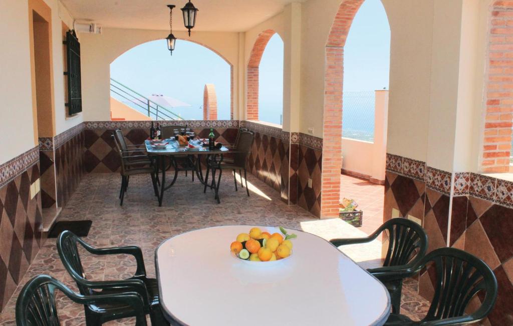 balkon ze stołem i krzesłami oraz stołem z owocami na nim w obiekcie Gorgeous Home In Torrox With Kitchen w mieście Torrox