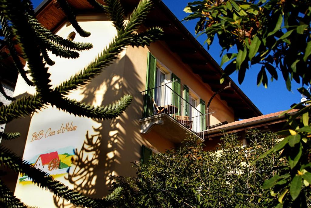 a building with a balcony and a tree at B&B Casa al Mulino in Cannero Riviera
