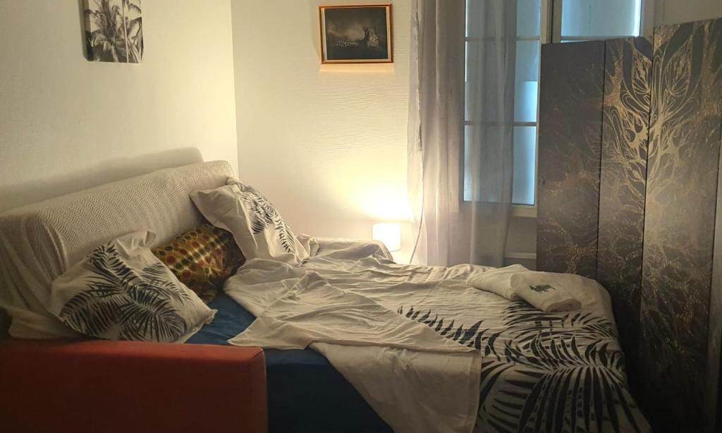 - un lit avec des draps et des oreillers dans l'établissement Studio cosy Bassens 33530, à Bassens