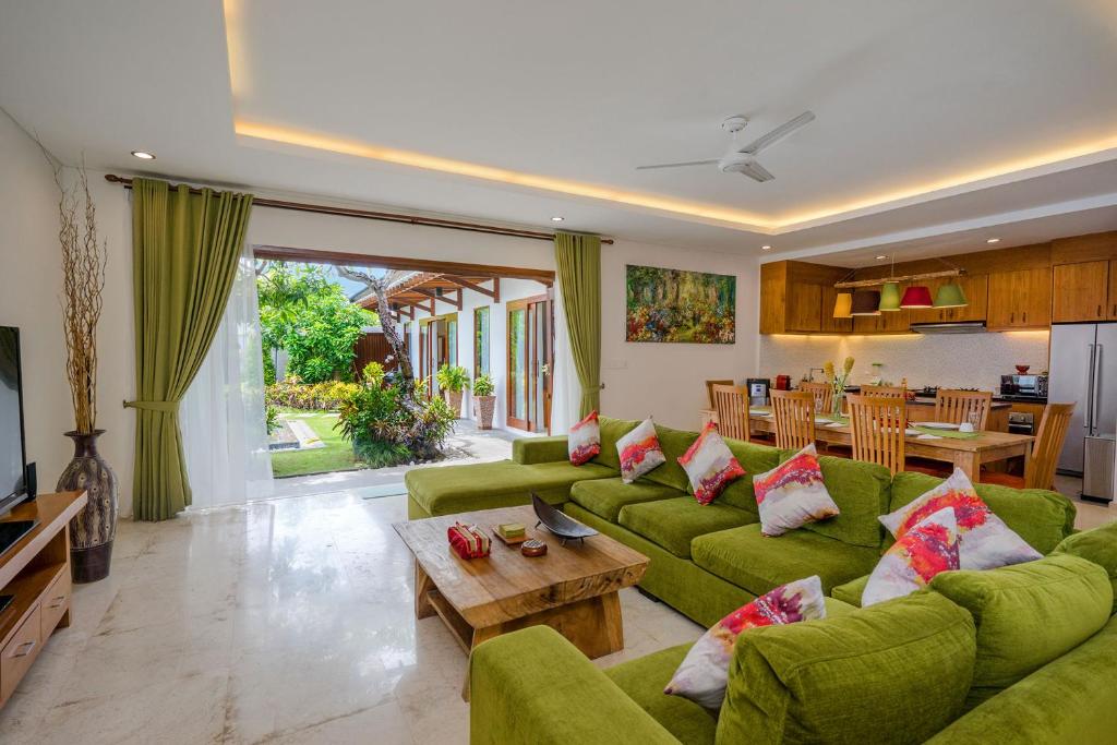a living room with green couches and a table at Delight ART Villas in Seminyak