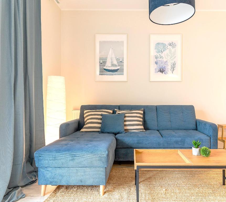 a blue couch in a living room with a table at Marina Summer - przy jeziorze, Netflix, TV55", parking podziemny i winda in Iława