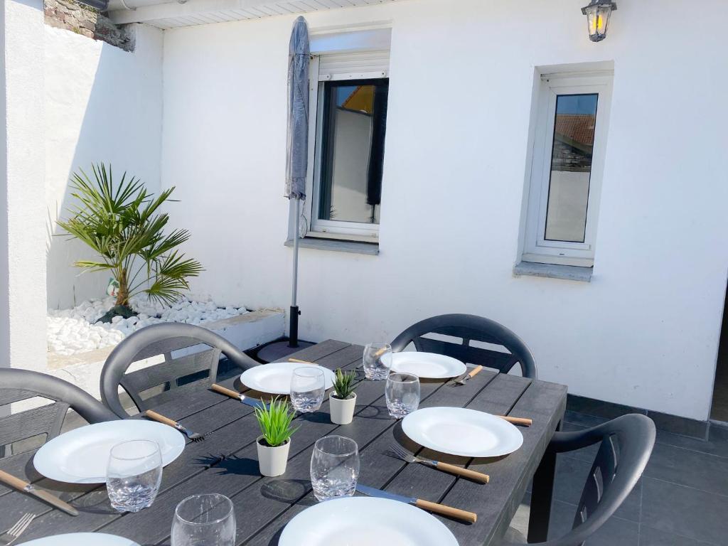 - une table en bois avec des chaises et des assiettes dans l'établissement Les Dunes 1, à Sangatte