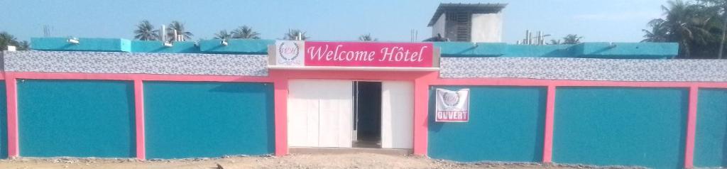 JacquevilleにあるWelcome Hôtelのピンクの看板が付いたカラフルな建物