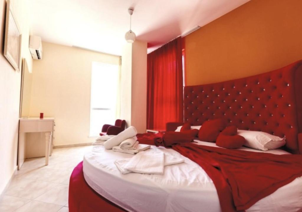 a bedroom with a large bed with a red headboard at Hotel Garden in Vlorë