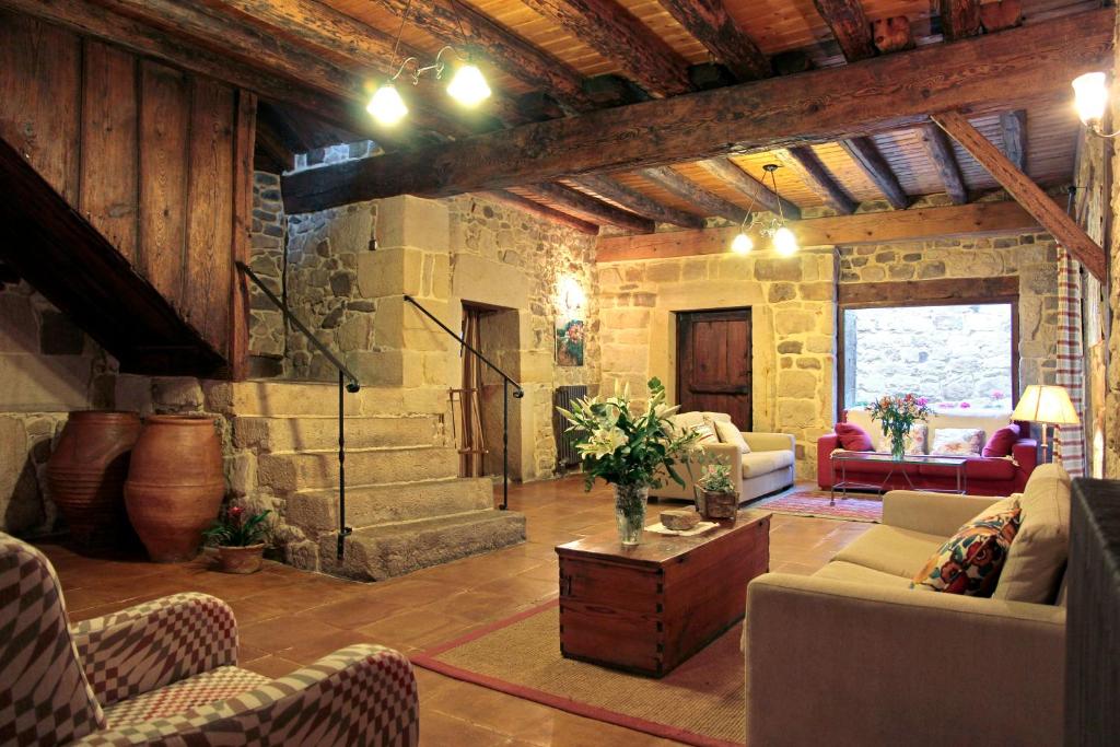 sala de estar con muebles y pared de piedra. en La Casona de El Royo, en El Royo