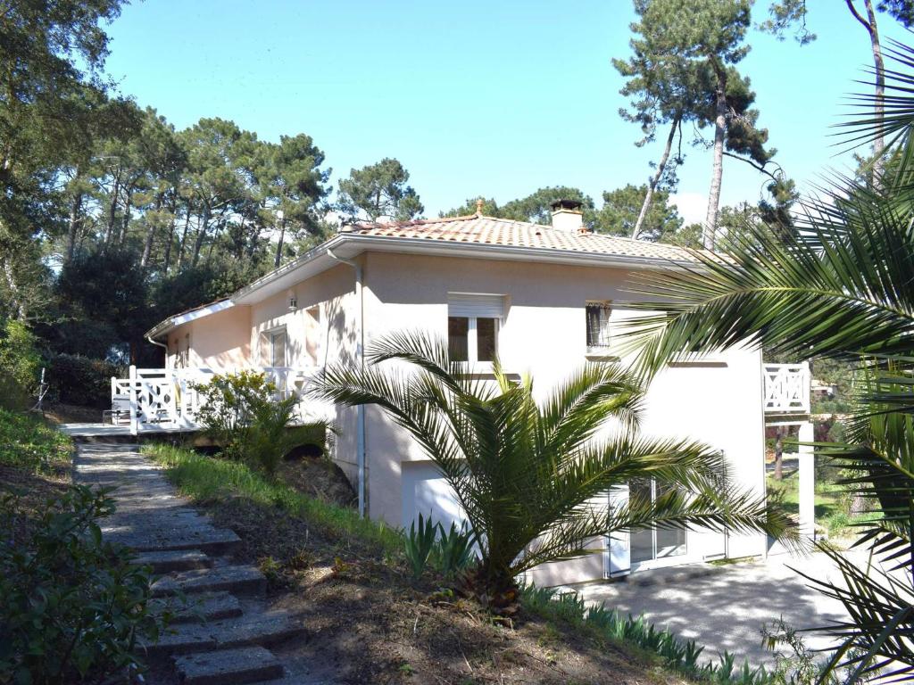 une maison blanche avec un palmier devant dans l'établissement Spacieuse villa familiale avec terrasses à 500m du Bassin - FR-1-736-21, à Lège-Cap-Ferret