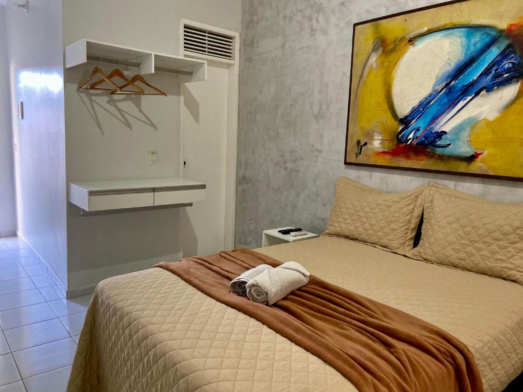 a bedroom with a bed with a painting on the wall at Studio Brownie em Capim Macio in Natal
