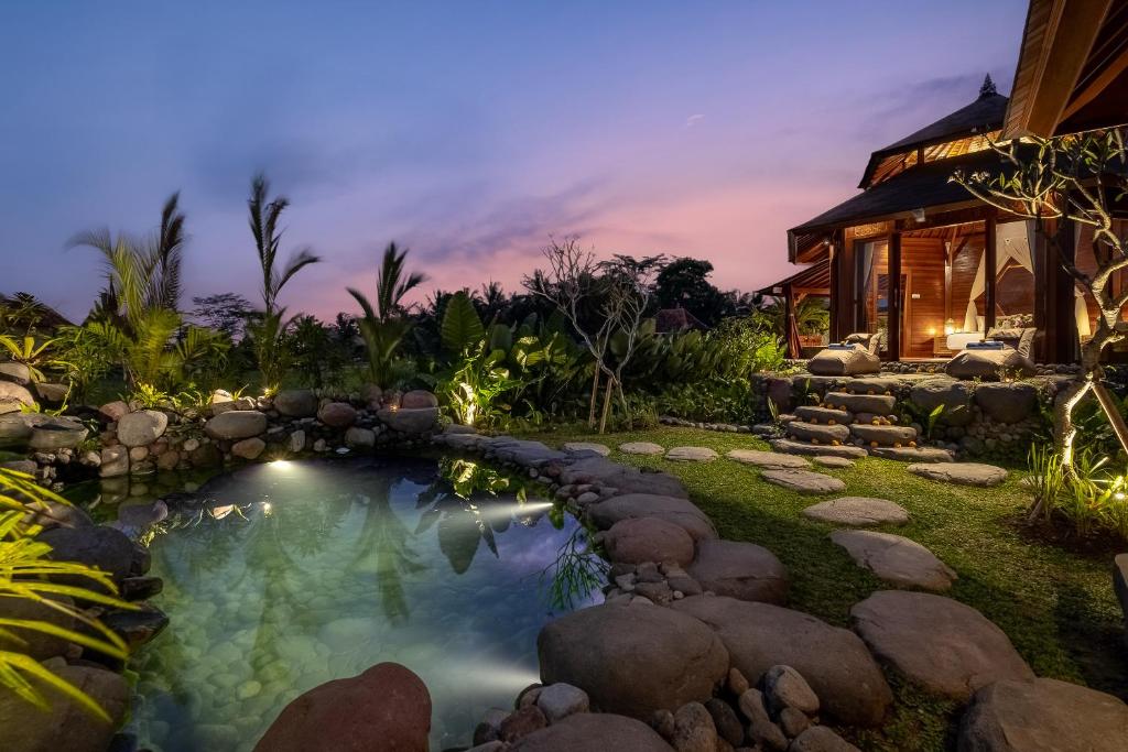 Un patio trasero con piscina y una casa. en Wooden Stone Eco Villa, en Ubud