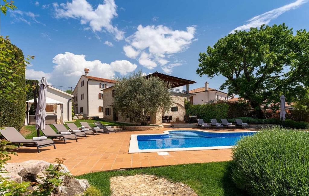 une piscine dans une cour avec des chaises et une maison dans l'établissement Villa Pilato, à Vižinada