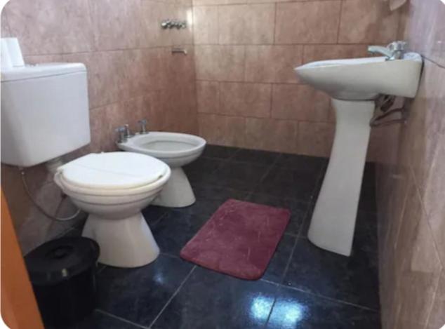 a bathroom with a white toilet and a sink at El retiro, casa de campo in San Antonio de Areco
