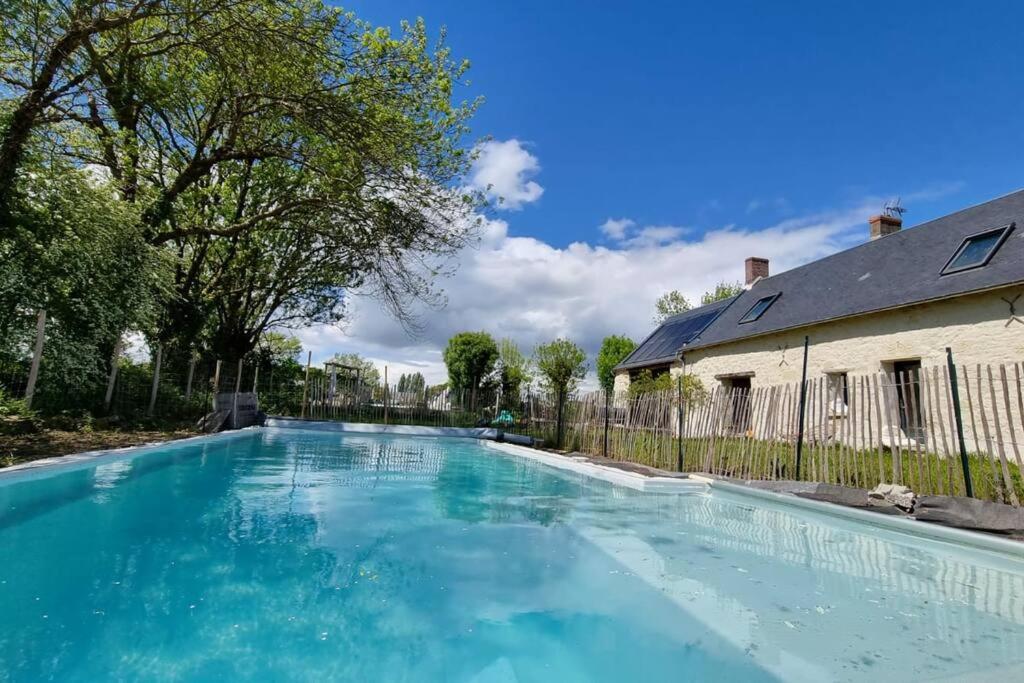 une piscine avec de l'eau bleue devant une maison dans l'établissement La Maison As de Cœur, 5 suites, 10 personnes, à Allonnes