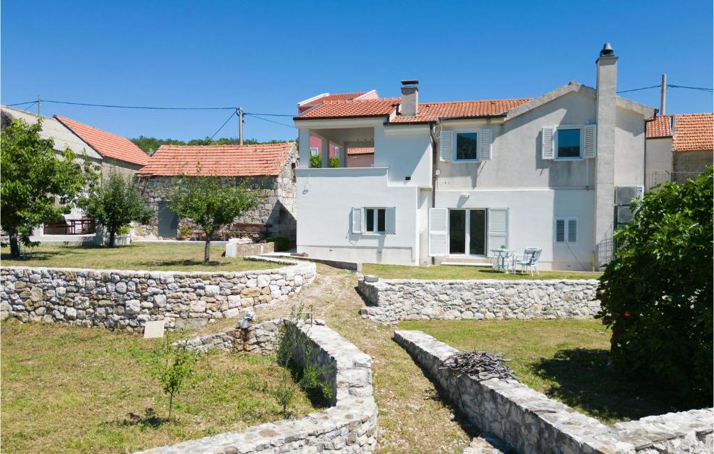 a large white house with a stone wall at 1 Bedroom Amazing Apartment In Podgrade in Slime
