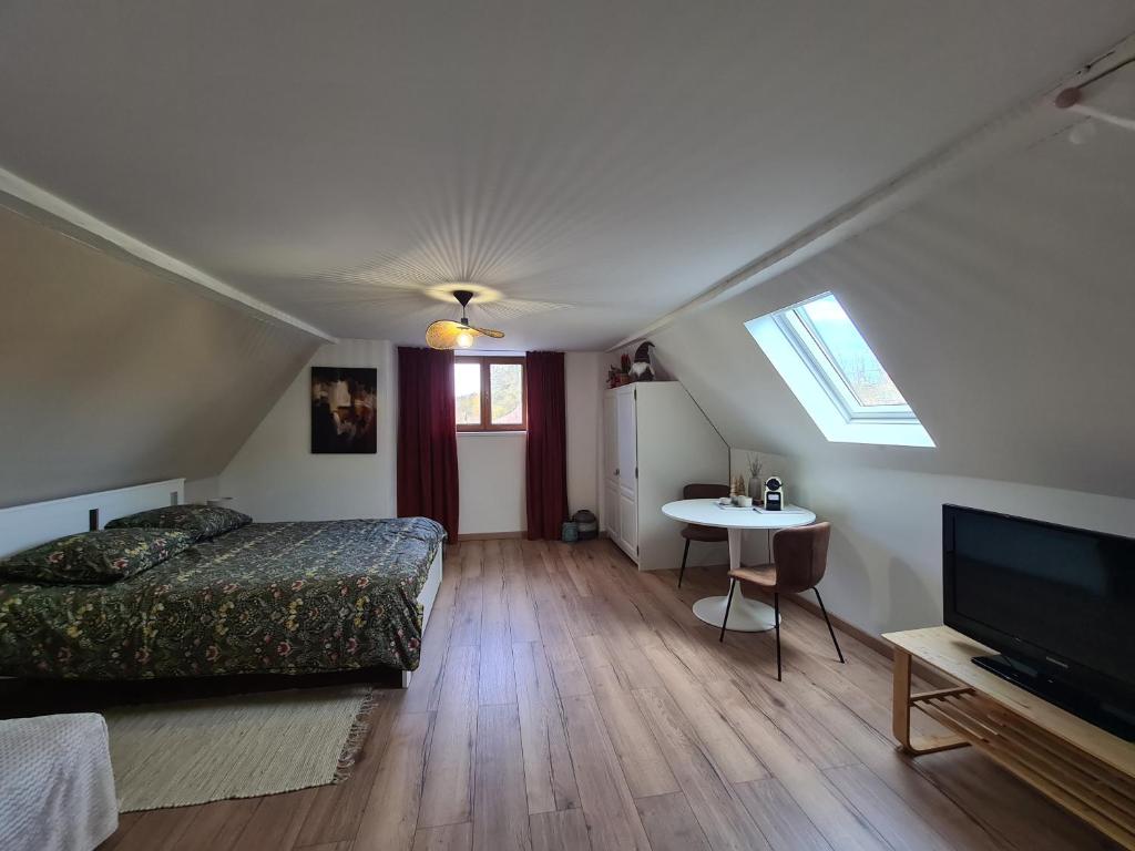 a bedroom with a bed and a table and a tv at L'escale champêtre in Uhrwiller