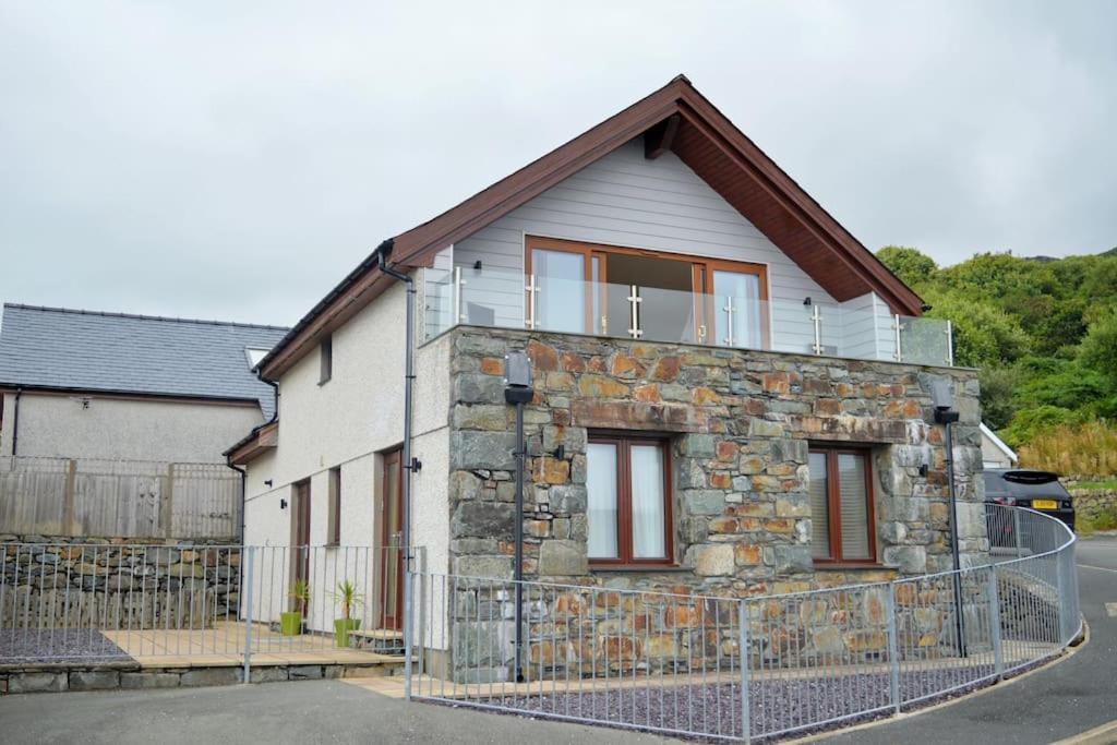une maison en pierre avec une clôture devant elle dans l'établissement Ruby's Watch, à Barmouth