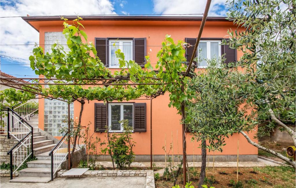 pomarańczowy dom ze schodami i drzewami przed nim w obiekcie 2 Bedroom Lovely Apartment In Fazana w Fažanie