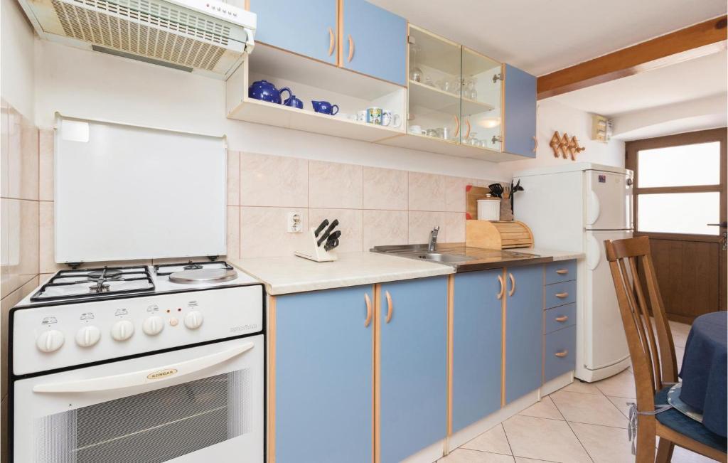 kuchnia z niebieskimi szafkami i białą płytą kuchenną w obiekcie 3 Bedroom Beautiful Home In Veli Iz w mieście Veli Iž