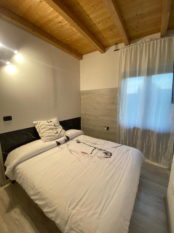 a bedroom with a large white bed with a window at Agriturismo La Falesia in Bagnasco