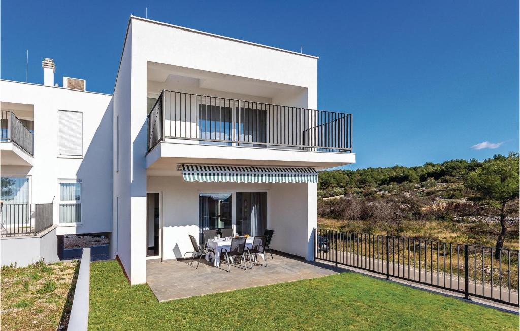 a white house with a balcony with a table and chairs at Three-Bedroom Holiday Home In Brodarica in Brodarica