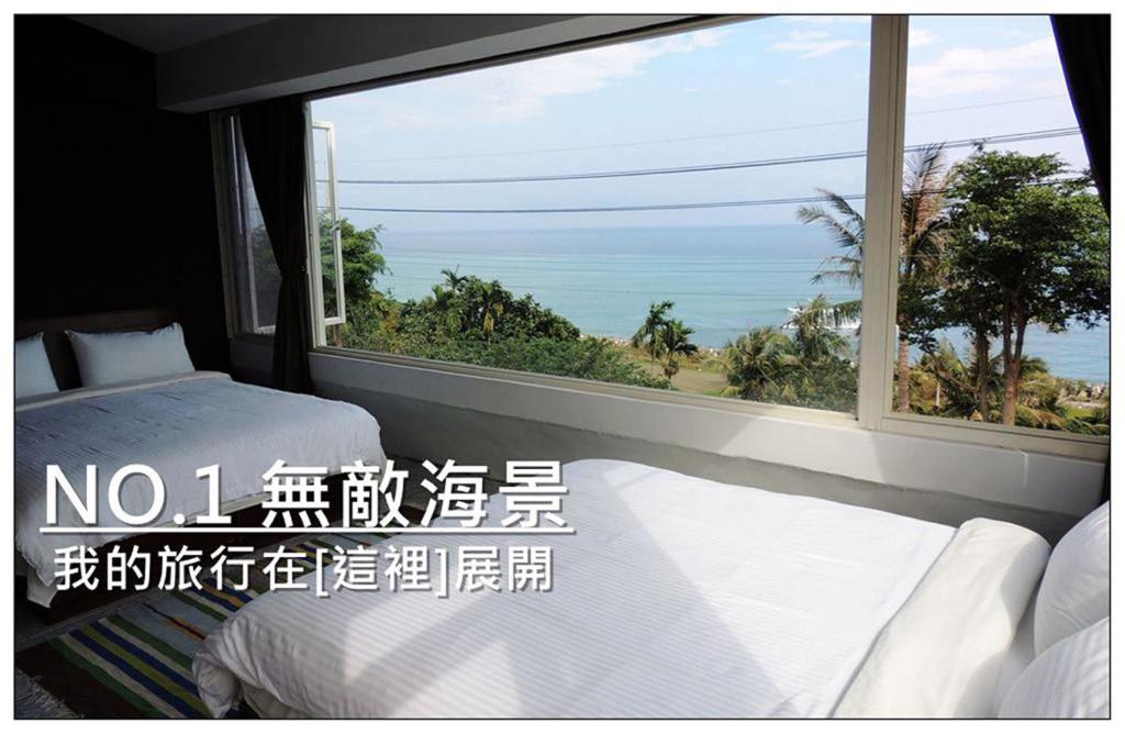 a room with two beds and a large window at Donghe surf shop & Hostel in Donghe