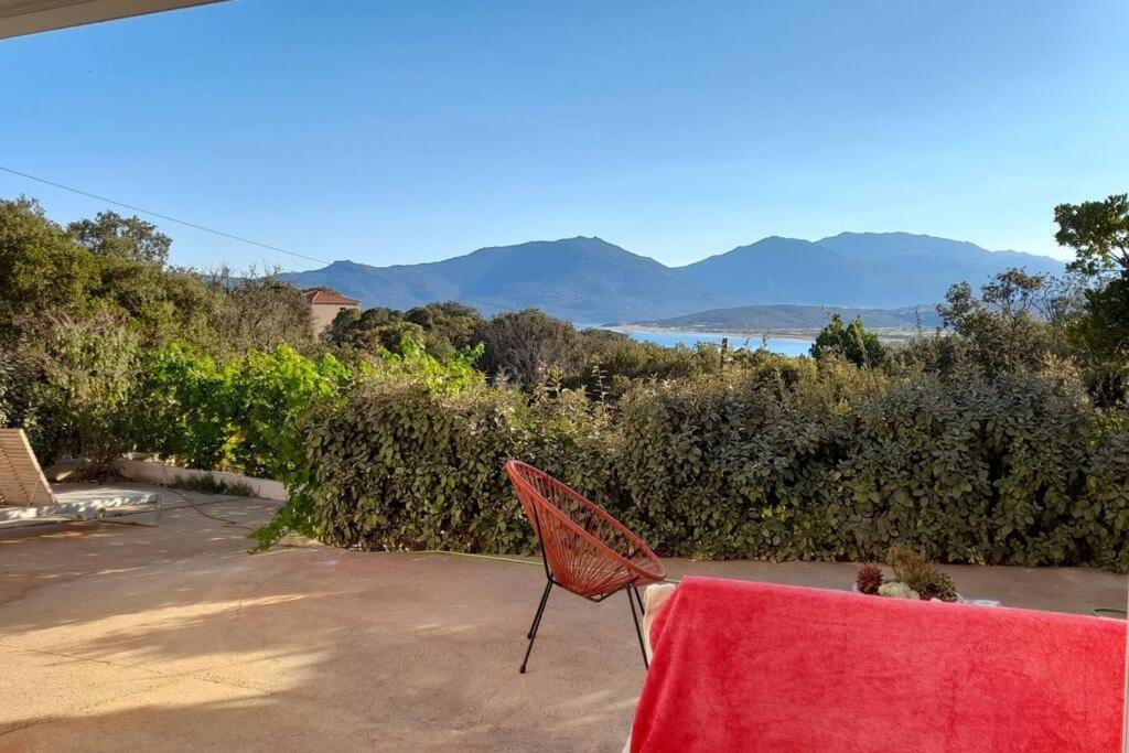 une chaise rouge assise sur une terrasse avec une table dans l'établissement Appartement T2 Belvedere campomoro, à Portigliolo