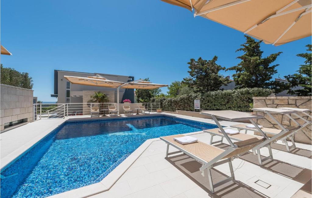 a swimming pool with lounge chairs and an umbrella at Amazing Apartment In Novalja With Wifi in Novalja