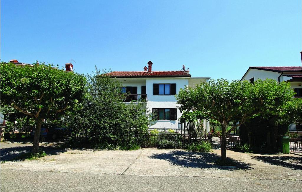 Biały dom z drzewami przed nim w obiekcie Awesome Apartment In Umag With Wifi w mieście Umag