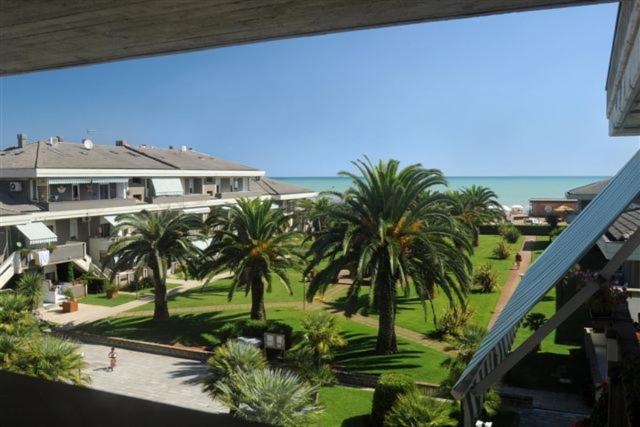 Blick auf einen Garten mit Palmen und einem Gebäude in der Unterkunft Residence Leonardo sul mare in Silvi Marina