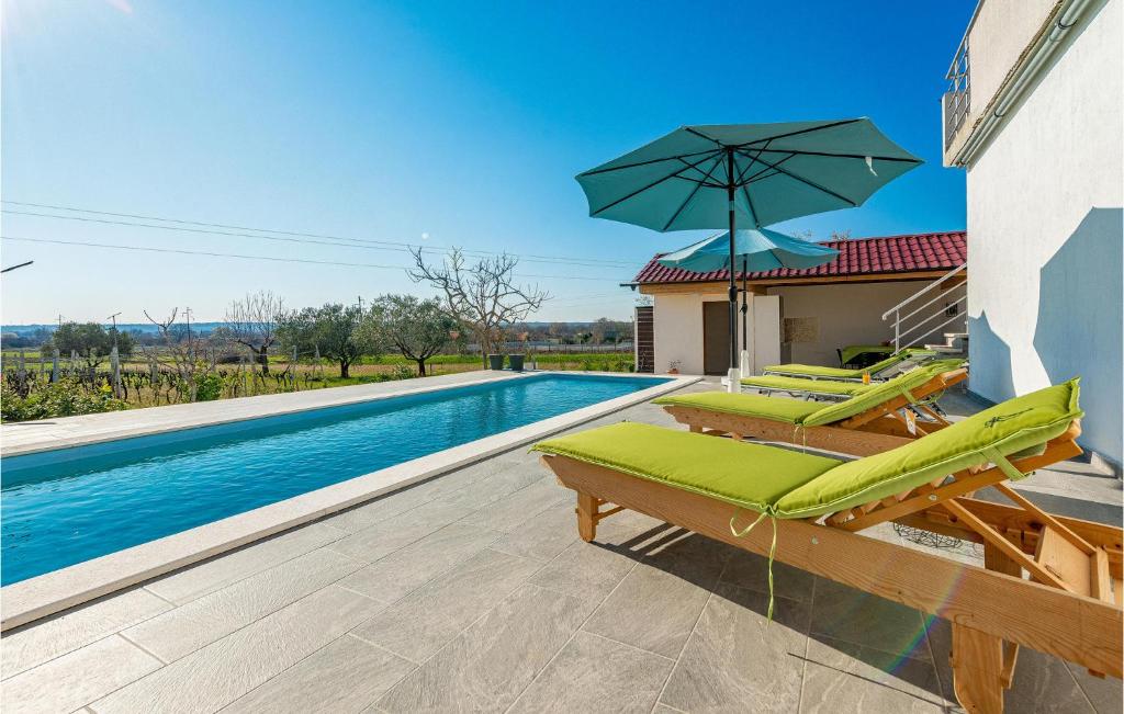 a swimming pool with lounge chairs and an umbrella at Villa Sunset in Galovac