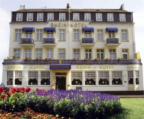 Rhein-Hotel في أندرناخ: فندق ابيض كبير بالورود امامه