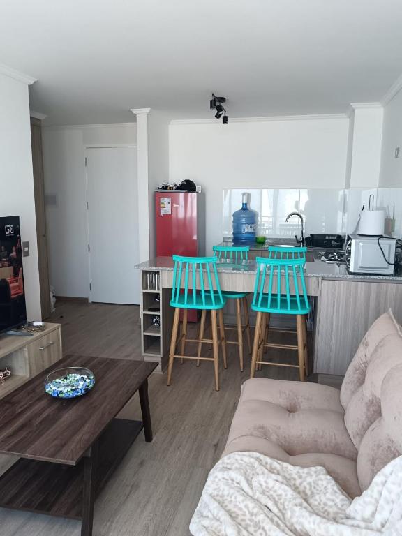a living room with a table and chairs and a kitchen at Departamento familiar Iquique in Iquique