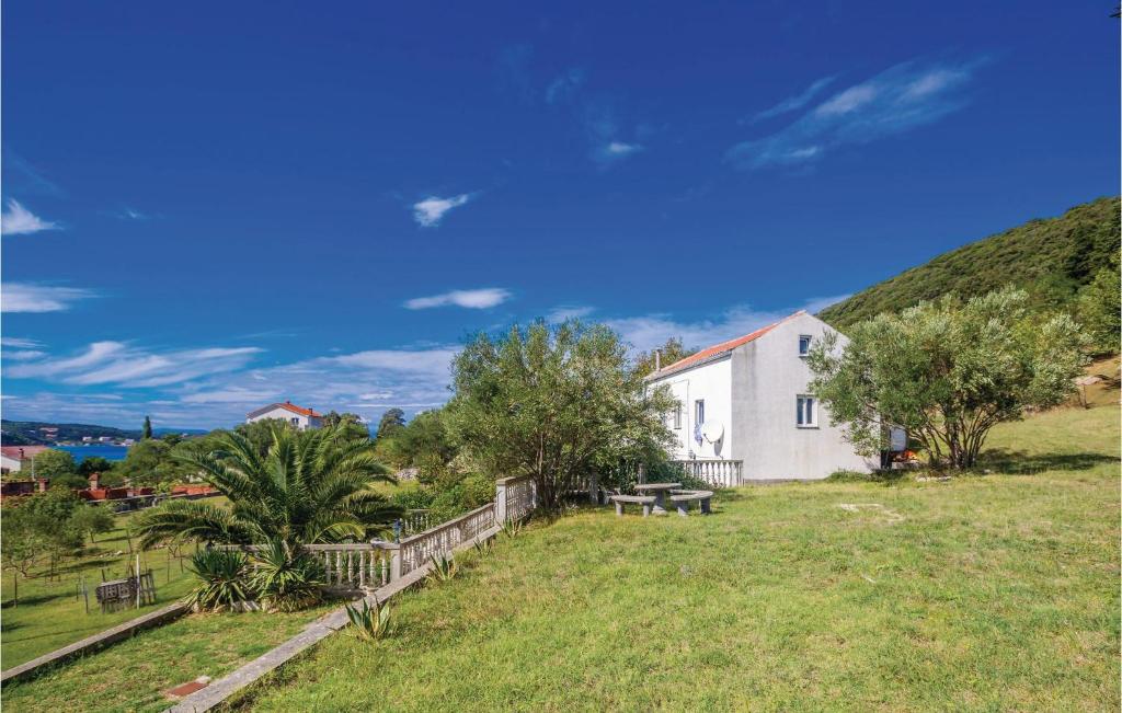 a white house in a field with a hill at Lovely Home In Supetarska Draga in Supetarska Draga