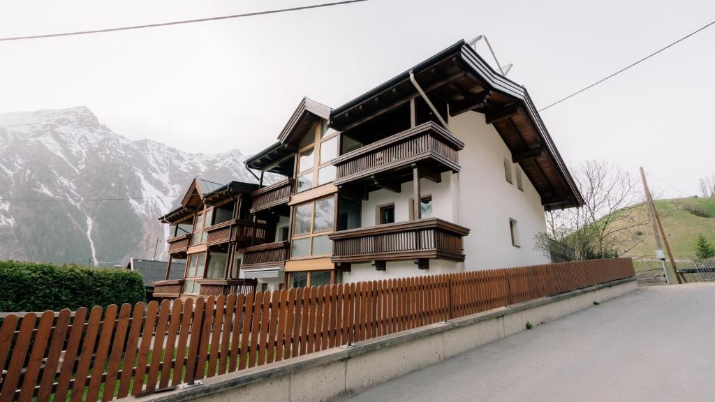 a building with a fence next to a mountain at Apart Gipfelglück in Längenfeld