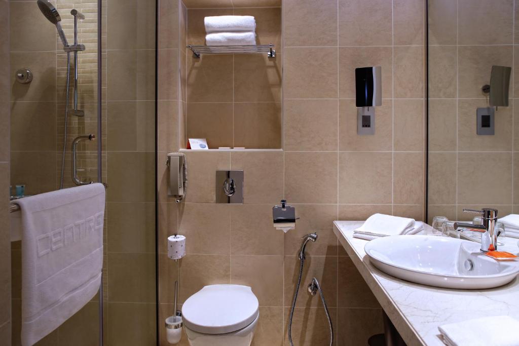 a bathroom with a shower and a toilet and a sink at Centro Al Manhal by Rotana in Abu Dhabi