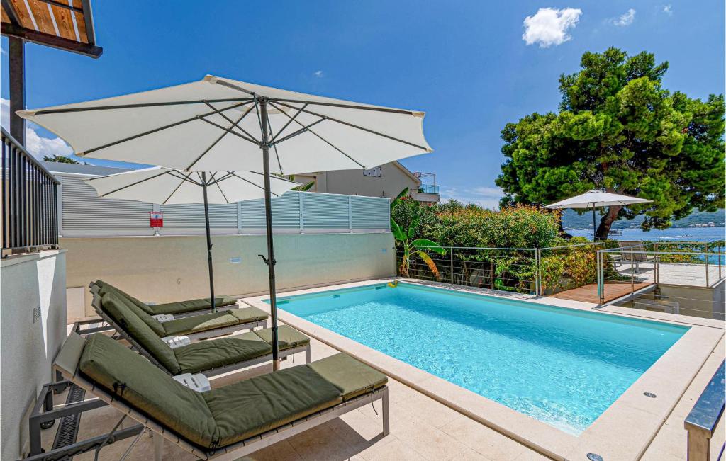 a pair of chairs and an umbrella next to a swimming pool at Stunning Home In Viganj in Viganj