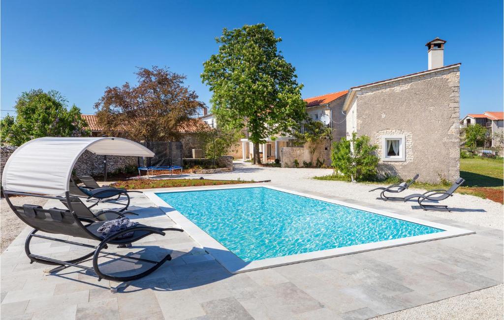 a swimming pool with two chairs and an umbrella at Amazing Home In Modrusani With Wifi in Modrušani