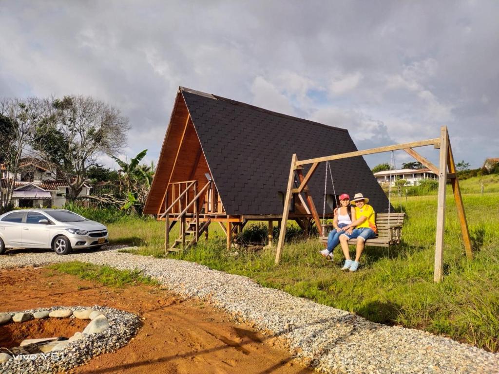 two people sitting on a swing in front of a house at Lago Cristal Chalets in Bucaramanga