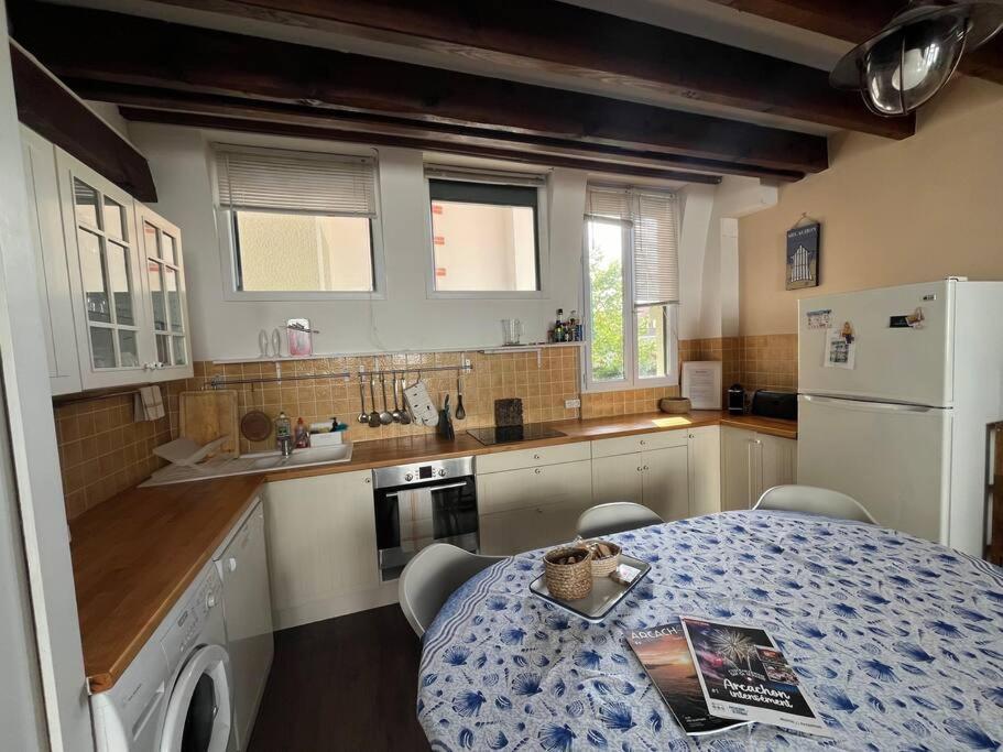 une cuisine avec une table et un réfrigérateur blanc dans l'établissement Maison de ville centre Arcachon, à Arcachon