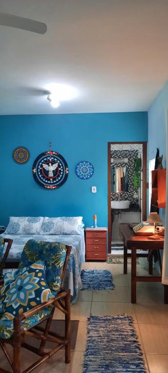 a room with a blue wall with a bed and a table at Chalé Puertas y Ventanas in São Sebastião