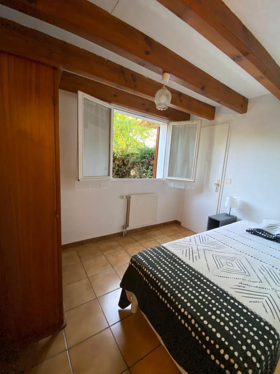 a bedroom with a bed and a window at Maison à 800m de la plage classée 1 étoile in Capbreton
