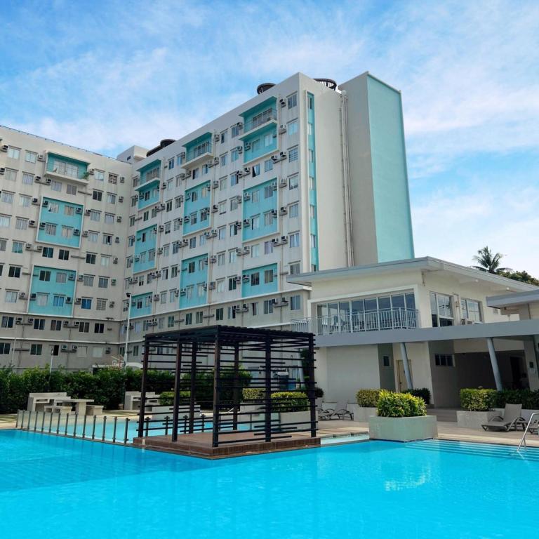 a hotel with a swimming pool in front of a building at Oceanview 2-bedroom Condo Unit in Dumaguete
