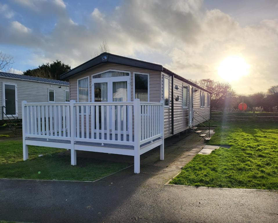 a tiny house with a white porch and the sun at Holiday Home at Combe Haven, St Leonards, Hastings in St. Leonards