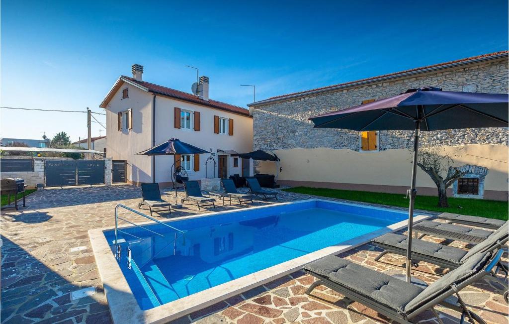 una casa y una piscina con sombrillas y sillas en Villa Druskovic, en Umag